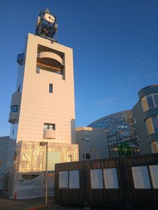 Klukkan á aðaltorginu gnæfir yfir gámunum  sem hýsa þjónustuverið.